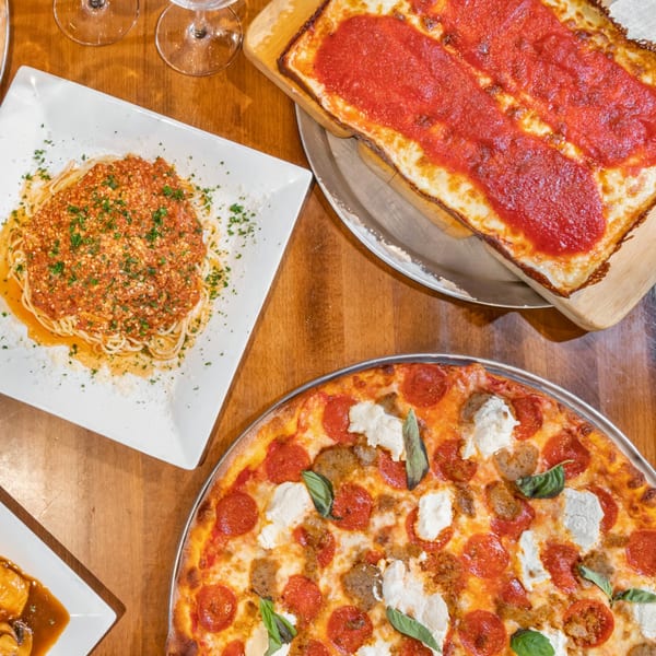 Overhead view of Bella Napoli's spaghetti, Sicilian pizza, and a round pepperoni and sausage pizza.