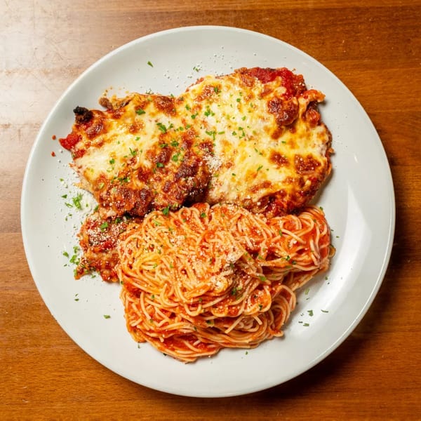 Chicken parmesan with melted cheese and red sauce, served with a side of spaghetti.