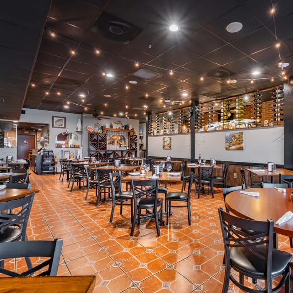 Empty dining room at Bella Napoli Pizzeria & Restaurant with tables, chairs, and wine racks.