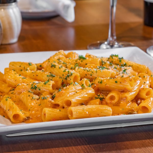Rigatoni pasta in a creamy orange sauce, topped with grated cheese and parsley at Bella Napoli.