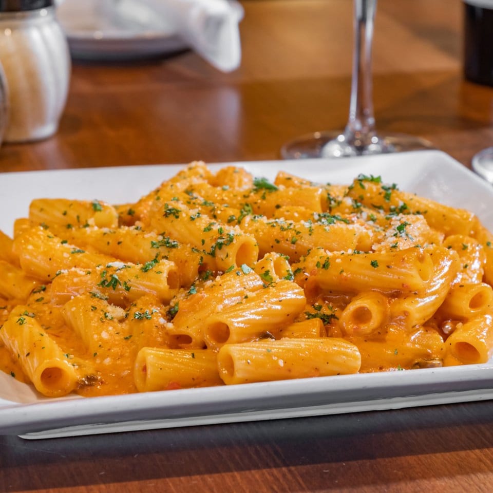 Rigatoni pasta in a creamy orange sauce, topped with grated cheese and parsley at Bella Napoli.
