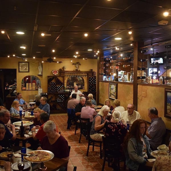 Diners enjoy Italian food and wine in the warm, inviting atmosphere of Bella Napoli Pizzeria & Restaurant.