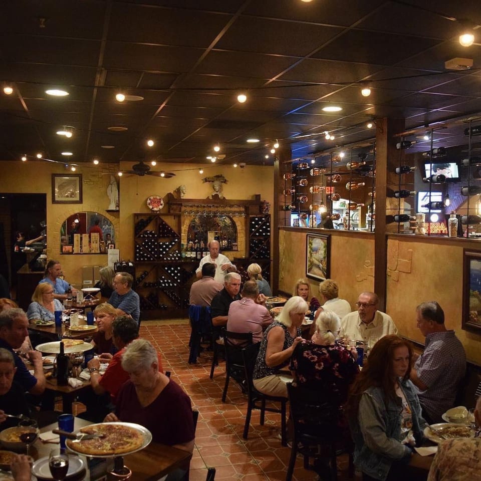 Diners enjoy Italian food and wine in the warm, inviting atmosphere of Bella Napoli Pizzeria & Restaurant.