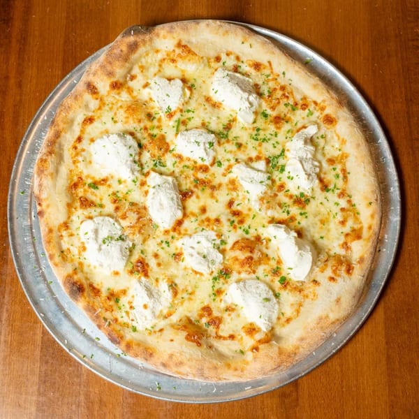 White pizza with dollops of ricotta cheese and sprinkled parsley on a metal pan.
